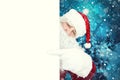 Authentic Santa Claus pointing at a blank white poster with copy space