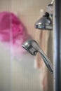 Authentic shower close up with showerhead and pink sponge washcloths.