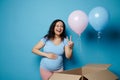 Authentic amazed expectant mother holding hand on her pregnant belly, showing two fingers, expecting twins. Baby shower Royalty Free Stock Photo