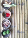 Authentic Thai red curry ingredients in coconut shells on bamboo table