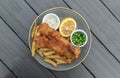 Authentic traditional british cuisine Fish and Chips served with French fries, Green peas, cut Lemon and Tartar sauce Royalty Free Stock Photo