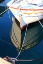 Authentic white wooden boat and ropes on crystal clear sea waters and the sun reflection, calm water and cordage in the soft