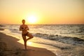 Authentic woman in swimsuit doing yoga vrikshasana on the beach in the morning. Real unretouched shape girl silhouette Royalty Free Stock Photo