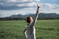 Authentic young woman standing under dramatic spring sky with her arm raised in victorious gesture