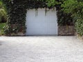 AUthenticity of a white garage door under dense green leaves of ivy