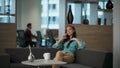 Authoritative manager talking phone at sofa. Smiling businesswoman at office