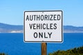 Authorized Vehicles Only road sign. Calm water of the bay and coastline is visible in the distance