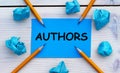 AUTHORS - word on blue paper on a light background with crumpled pieces of paper and pencils