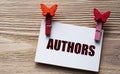 AUTHORS - word on a white sheet with beautiful clothespins on a wooden background