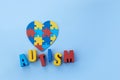 Autism awareness concept with puzzle shape of heart and word autism on blue background. Royalty Free Stock Photo