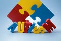 Autism awareness concept with puzzle and word autism on blue background. Royalty Free Stock Photo