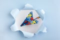 Autism awareness day or month. Paper plane in origami style with autism awareness puzzle ribbon in blue torn hole paper.