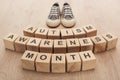 Autism awareness month words made of wooden blocks near grey children sneakers.