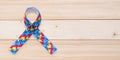 Autism awareness ribbon in puzzle or jigsaw pattern isolated on wood background with clipping path for World Autism Awareness Royalty Free Stock Photo