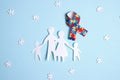 Autism concept with family paper silhouette and puzzle awareness ribbon on a blue background Royalty Free Stock Photo