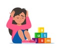 Autism concept. Girl feeling lonely. Sad boy sitting on floor surrounded by cubes toys with word autism. Child plugged ears with