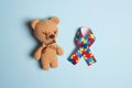 Autism concept with toy bear and puzzle awareness ribbon on a blue background Royalty Free Stock Photo