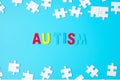 AUTISM text with white puzzle jigsaw pieces on blue background. Concepts of health, Autistic Spectrum disorder and world Autism Royalty Free Stock Photo