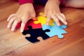 Autistic child`s hands playing jigsaw puzzle symbol of autism spectrum disorder. Royalty Free Stock Photo
