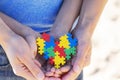 Autistic kid hands supported by mother holding multicolored puzzle heart. World autism awareness day concept Royalty Free Stock Photo