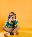 Autistic kid. Seven years old boy sits on the floor in yellow room with headphones. Music therapy. Portrait of child