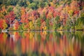 Autmn foliage reflecting on lake water with lake house and dock Royalty Free Stock Photo