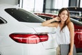 Female seller holding black folder looking at camera at car dealership. Royalty Free Stock Photo