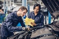 Auto car repair service center. Two mechanics - man and woman examining car engine Royalty Free Stock Photo