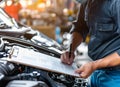 Auto check, car service shop concept. Automobile repairman writing job checklist on clipboard, mechanic checking engine Royalty Free Stock Photo