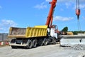 Auto crane loads an old concrete slab into a dump truck at a construction site.