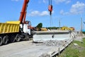 Auto crane loads an old concrete slab into a dump truck at a construction site.