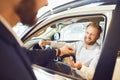 Auto dealer shows a new car to a man
