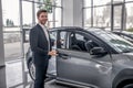 Brown-haired male opening car door in showroom