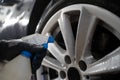 Auto detailing worker applies chemistry to wheels. Professional car wheel wash.