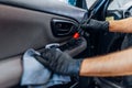 Auto detailing, worker cleans door trim with brush