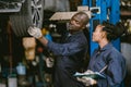 Auto garage worker Black African working together to fix service car vahicle wheel support together Royalty Free Stock Photo