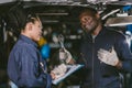 Auto garage worker Black African working together to fix under car service working togerher walking smile