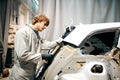 Auto repair worker flatten and align metal body car with hammer in garage Royalty Free Stock Photo