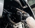 An auto mechanic applies anti-corrosion mastic to the underbody of a car.