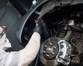 An auto mechanic applies anti-corrosion mastic to the underbody of a car.