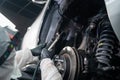 An auto mechanic applies anti-corrosion mastic to the underbody of a car.