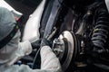 An auto mechanic applies anti-corrosion mastic to the underbody of a car.