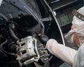 An auto mechanic applies anti-corrosion mastic to the underbody of a car.