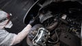 An auto mechanic applies anti-corrosion mastic to the underbody of a car.