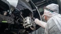 An auto mechanic applies anti-corrosion mastic to the underbody of a car.