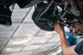 Auto mechanic asian checking bush-bolt under double wishbone suspension by hand with tools car lift Royalty Free Stock Photo