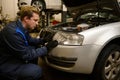 Auto mechanic in car service adjusting headlights on car in the repair shop garage. Auto service, car repair and warranty Royalty Free Stock Photo