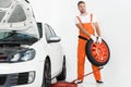 auto mechanic carrying car tire