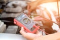 auto mechanic check car battery voltage by voltmeter multimeter Royalty Free Stock Photo