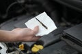 Auto mechanic checking engine oil dipstick in car